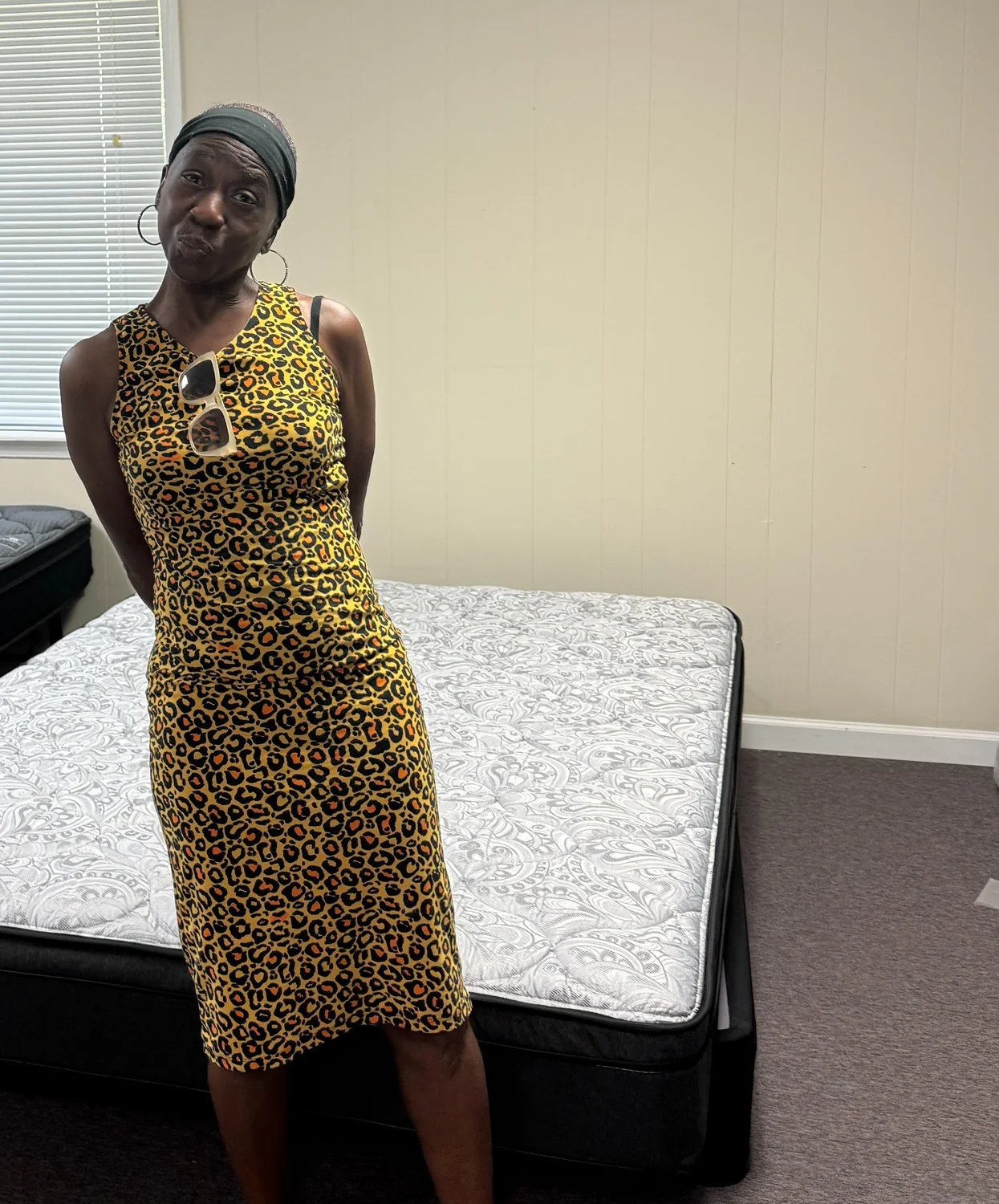 Happy customer in a gold dress standing in front of a mattress